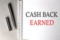 CASH BACK EARNED text on a notebook with pen on grey background Royalty Free Stock Photo