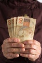 Cash bills from brazilian currency. Old retired person paying in cash Royalty Free Stock Photo