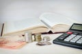 Cash notes, stacks of coins and a calculator in front of an open book. Concept of expensive education and low scholarship
