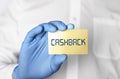 Cashback word on golden bank card in hands of man in protective gloves