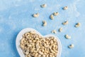 Cashew nuts in heart shaped plate on blue background. Healthy vegetarian snacks. Protein-containing food. Flat lay, Copy space for Royalty Free Stock Photo