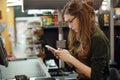 Cashier lady on workspace in supermarket shop using mobile Royalty Free Stock Photo