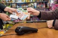 Cashier take euro banknote from consumer hand