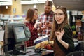 Cashier woman on workspace make okay gesture.