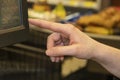 Cashier womans hand using touch screen cash register with groceries on conveyor belt blurred in background -selective focus and