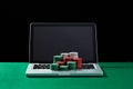 Casino chips on keyboard notebook at green table.