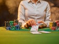 Casino. The croupier is holding playing cards and there are a lot of chips next to him. Gaming green table. Risk, luck, pastime. Royalty Free Stock Photo