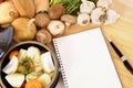 Casserole dish with organic vegetables and herbs on kitchen worktop with cookbook or recipe book Royalty Free Stock Photo