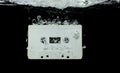 Cassette retro vintage Tape fall into clear water with air bubble. Black retro vintage cassette magnetic tape drop to wash old