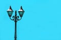 Cast iron antique lamppost against vibrant sky blue colored concrete wall