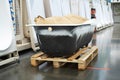 A cast iron bathtub on a wooden pallet is for sale in a specialist store. Foreground. Selective focus