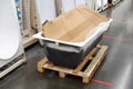 Cast iron bathtub on a wooden pallet in a store. Trade and production of sanitary ware for residential buildings. Selective focus