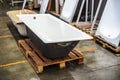 Cast iron bathtub on a wooden pallet. Warehousing and sale of plumbing fixtures in the store. Close-up