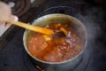 Cast iron cauldron boiling a goulash stew over a wood burning stove made from red bricks in the backyard of a rural house in