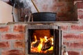 Cast iron cauldron boiling a goulash stew over a wood burning stove made from red bricks in the backyard of a rural house in