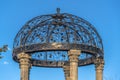 Cast iron gazebo with dome roof supported by five white stone pillars Royalty Free Stock Photo