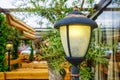 Cast iron lamp in an idyllic garden with wooden benches and tables
