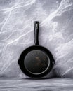 cast iron pan with black handle, showing signs of wear and rust, placed on textured gray surface. This captures rustic charm of Royalty Free Stock Photo