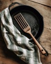 Cast iron pan kitchen spatula wooden handle striped towel rustic wood surface Royalty Free Stock Photo