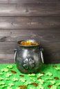 Cast iron pot, decorated by four-petal lucky shamrock leaf, full of leprechaun gold treasure, clover leaves and gold coins on Royalty Free Stock Photo