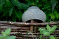 Cast iron pot on a vine fence surrounded by greenery