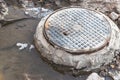 A cast-iron sewer manhole surrounded by a puddle of water at a construction site. Construction of sewer wells Royalty Free Stock Photo