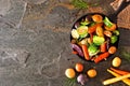 Cast iron skillet of roasted autumn vegetables, above view side border on a dark slate background Royalty Free Stock Photo