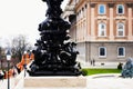 cast iron, wrought iron and forged steel decorative, ornate shiny black lamppost detail. soft blurred stone building elevation Royalty Free Stock Photo