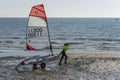 female contestant pulling her boat on glittering sand at Open Skiff regatta, Castiglione della Pescaia, Italy