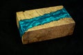 blue epoxy resin with nature burl maple wood cube on black background