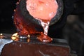 Casting liquid red hot metal from crucible held with tongs