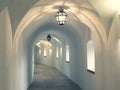 Castle corridor lightened with overhead lighting. Interior of a long corridor with white walls and arches Royalty Free Stock Photo