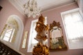 Castle interior. Antique mirror in a carved frame. Hall with a baroque staircase. Castle Duchcov, Czech Republic