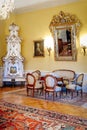 Castle interior. Tea room, wood carved chairs and table. Mirror in a gilded frame. Antique ceramic stove. Renaissance castle