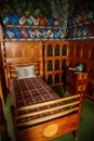 Castle interior, Wooden wall panels, color murals on walls, images of noble arms, bed with checkered bedspread, bedroom,