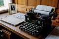 Castle interior, wooden writing desk, table near windows, black vintage antique typewriter, blank sheet of paper inserted,