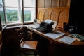 Castle interior, wooden writing desk, table near windows, black vintage antique typewriter, blank sheet of paper inserted,