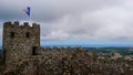 a flag waving on the tower of the Castle of the Moors under a cloudy sky with the cityscape in the background Royalty Free Stock Photo