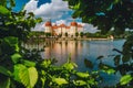 Castle Moritzburg in Saxony near Dresden. Framed by spring lush foliage leaves in foreground with reflection in pond