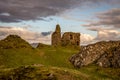 Castle Tarbert in the middle of the picture with rough lumpy rolling grass and a large rock on the right foreground with