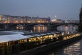 Bridge over the river in Prague in the evening with lots of lights, ships and restaurants on the shore