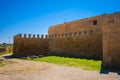 Castle wall with arrow slits protecting a simple square cathedral with a cross on it