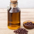 Castor beans and oil in a glass jar on wooden background