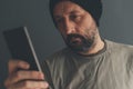 Casual adult male with cap looking at mobile phone