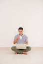 Casual asian man sitting on floor using laptop at home in the li Royalty Free Stock Photo