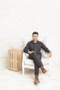 casual asian young man looking at camera while sitting at decorated room Royalty Free Stock Photo