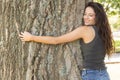 Casual attractive brunette embracing a tree with closed eyes