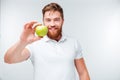 Casual bearded man holding green apple and looking at camera Royalty Free Stock Photo