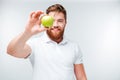 Casual bearded man showing green apple and looking at camera Royalty Free Stock Photo