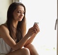 Casual beautiful woman typing the text on mobile phone sitting n